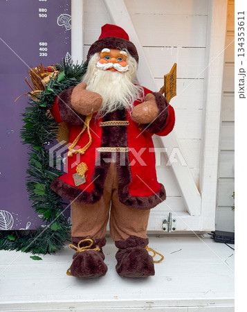 Santa Claus Christmas figurine standing on white wooden background. Holiday decor, festive tradition, winter atmosphere and seasonal celebration 134353611