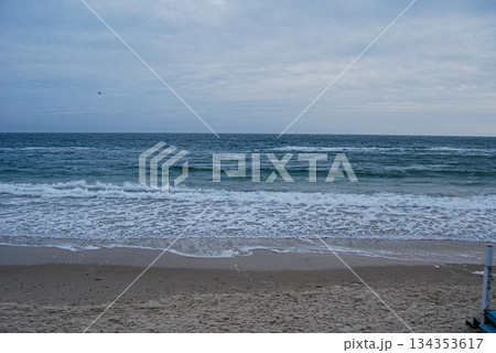 Sea waves crashing on a sandy shore under a cloudy sky. Waves crashing on a sandy shore under a cloudy sky, as seen from the railing on a beach in Odessa. 134353617