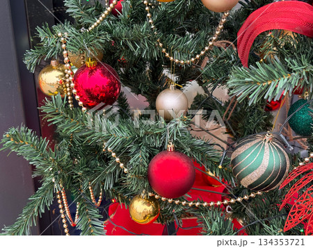 Detailed view of Christmas ornaments and garlands on decorated fir tree. Holiday decoration, winter celebration, festive atmosphere and traditional seasonal styling. 134353721