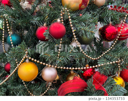 Detailed view of Christmas ornaments and garlands on decorated fir tree. Holiday decoration, winter celebration, festive atmosphere and traditional seasonal styling. 134353733