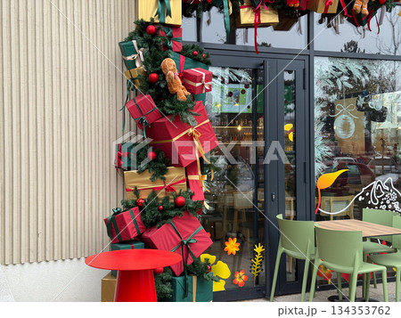 Christmas gift installation decorating cafe entrance with wrapped boxes and evergreen garlands. Festive urban hospitality, seasonal marketing, holiday atmosphere, winter celebration and consumer joy 134353762