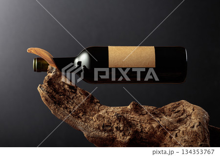 Bottle of red wine with empty label on a old wooden snag. 134353767