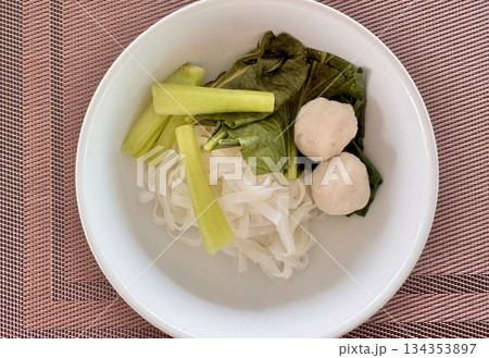 Delicious mouth-watering Asian noodles with meatballs in a white plate on the table Delicious mouth-watering Asian noodles with meatballs in a white plate on the table 134353897