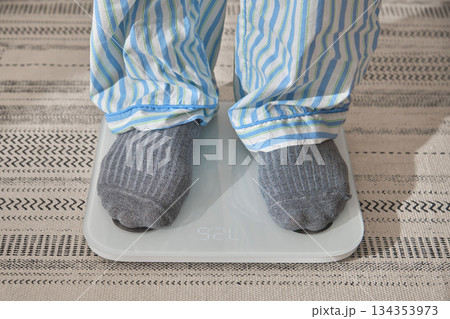 Person weighing on scale making new year resolutions Person weighing on scale making new year resolutions 134353973