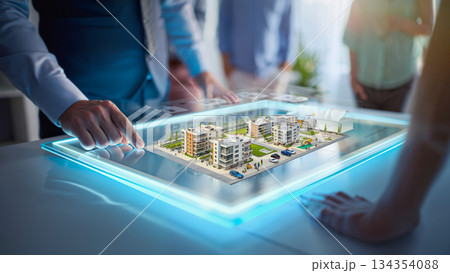Real Estate Development Vision on a Digital Platform. A businessman interacts with a digital tablet displaying a 3D model of a real estate development, featuring modern apartment buildings, trees, and 134354088