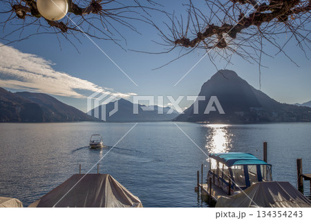 Small harbor and motorboat moving to coastline on Lake Lugano   or Lake Geneva 134354243