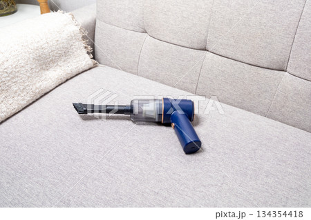 A blue vacuum cleaner is on a couch 134354418