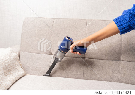 A person is vacuuming a couch 134354421
