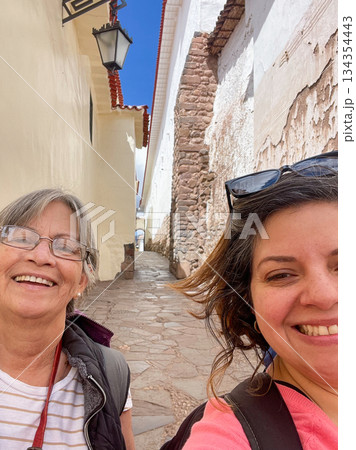 Two women smiling for a photo in a narrow alleyway Two women smiling for a photo in a narrow alleyway 134354443
