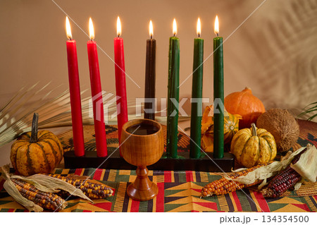 Kwanzaa Celebration Setup. A vibrant Kwanzaa display with colorful candles, fruits, corn, and a wooden chalice 134354500