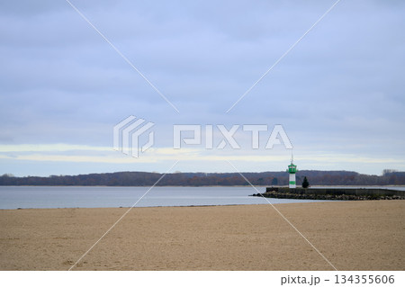 Coastal beacon atop pier with tranquil estuary underneath heavy clouds 134355606
