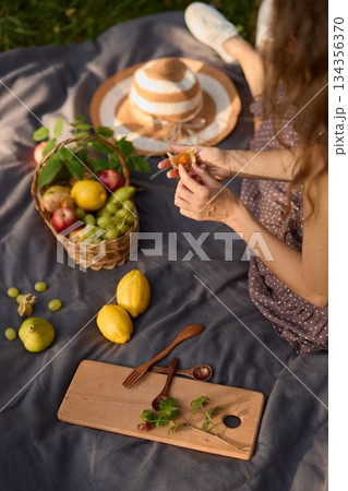 Cheerful young woman enjoys sunshine holding fruit outside 134356370