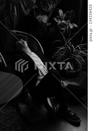Silhouetted person resting beneath foliage in subdued hues Silhouetted person resting beneath foliage in subdued hues 134356428