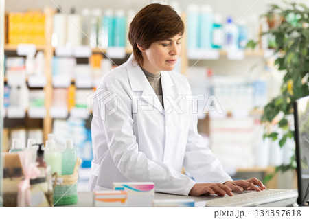 Female pharmacist working on computer at pharmacy counter 134357618