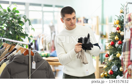 Young guy choosing gloves in clothing store Young guy choosing gloves in clothing store 134357632