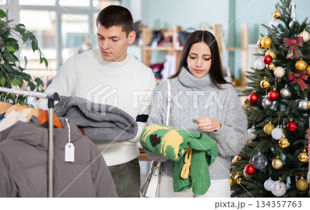Young couple choosing sweater in store Young couple choosing sweater in store 134357763