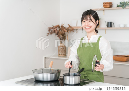 キッチンで料理をするエプロン姿の若いアジア人女性 134359813
