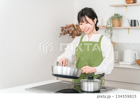 キッチンで料理をするエプロン姿の若いアジア人女性 キッチンで料理をするエプロン姿の若いアジア人女性 134359815