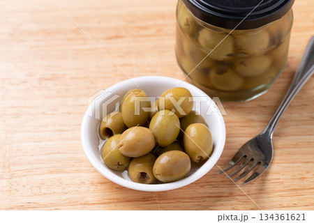 Pickled olives, Pitted green olives in a bowl and glass jar on wooden background 134361621
