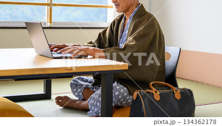 旅館和室でPC作業するシニア男性 134362178