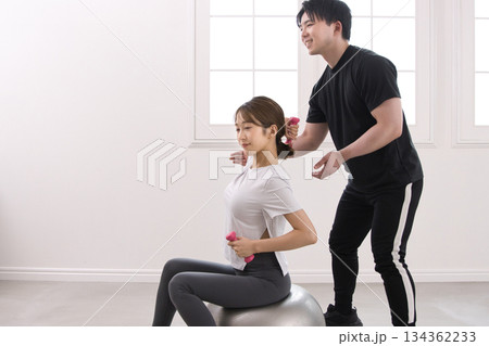 パーソナルトレーナーにトレーニングを受ける若い女性 134362233