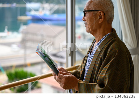 窓際でガイドブックを読む日本人シニア男性 134362238