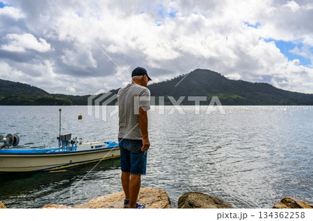 岩場から海を眺める中高年男性【撮影協力：隠 134362258