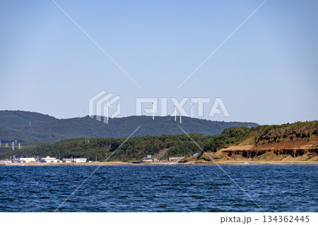 晴天の海と緑の丘に並ぶ風力発電の風車 晴天の海と緑の丘に並ぶ風力発電の風車 134362445