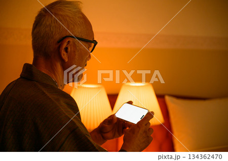 寝室でスマホを見る高齢男性 134362470
