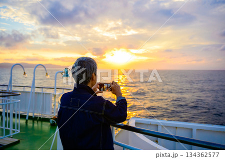 夕暮れのフェリーで夕日を撮る人 134362577