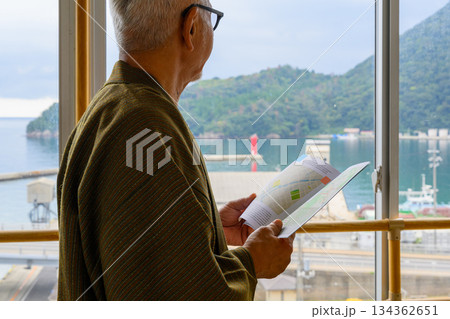 窓際で地図を見るシニア男性 窓際で地図を見るシニア男性 134362651