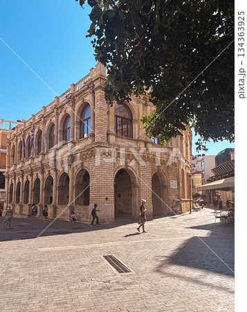 People enjoying a sunny summer day while walking around the historic venetian loggia building in heraklion, crete, exploring ancient architecture and greek culture 134363925