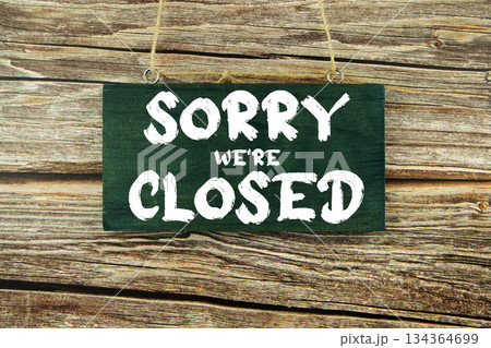 Sorry We're closed text written on wooden plank hanging on wooden background Sorry We're closed text written on wooden plank hanging on wooden background 134364699