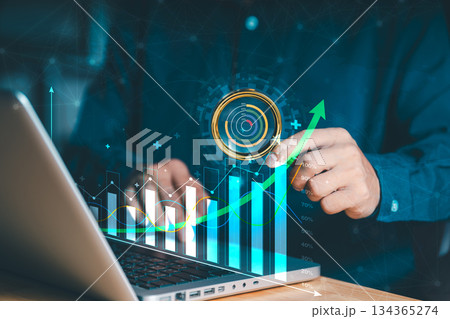 A person interacts with a laptop, Holographic display featuring a bar graph and an upward-trending line graph, symbolizing business growth and data analysis. Suggesting performance metrics or targets A person interacts with a laptop, Holographic display featuring a bar graph and an upward-trending line graph, symbolizing business growth and data analysis. Suggesting performance metrics or targets 134365274
