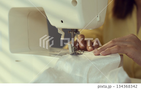 Woman clothing designer sews fabrics on a sewing machine. Needlework and handmade hobby. 134368342