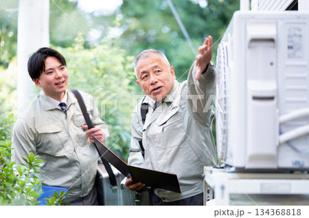 室外機をチェックするベテランと若手技術者 室外機をチェックするベテランと若手技術者 134368818