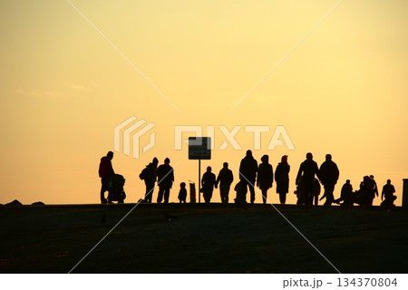 Silhouettes Walking by the Sea at Sunset. Silhouettes Walking by the Sea at Sunset. 134370804