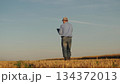 Farmer analyzing data on a tablet in a wheat field, Modern agriculture with digital technology, Checking wheat growth with a digital device, Using technology to enhance farming efficiency, Farmer 134372013