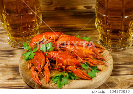 Boiled crayfish and two mugs of beer on a wooden table 134373089
