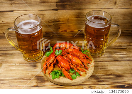 Boiled crayfish and two mugs of beer on a wooden table 134373090