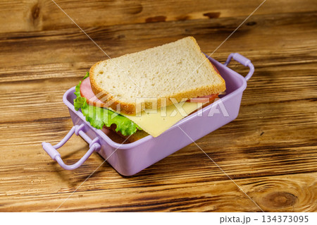 Lunch box with sandwiches on a wooden table Lunch box with sandwiches on a wooden table 134373095