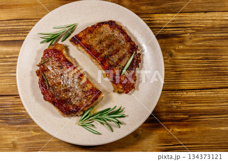 Grilled pork steaks with rosemary on wooden table. Top view Grilled pork steaks with rosemary on wooden table. Top view 134373121