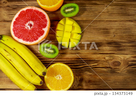 Assortment of tropical fruits on wooden table. Still life with bananas, mango, oranges, avocado, grapefruit and kiwi fruits 134373149