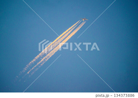 青空で夕陽に染まる飛行機雲 134373886