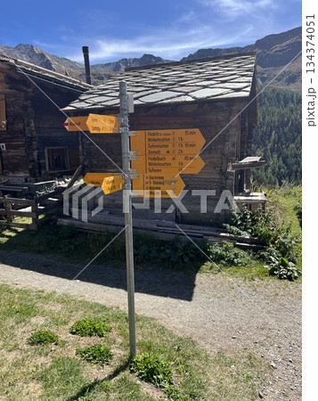 スイスアルプスハイキングコースの道標と岩屋根の山小屋 134374051