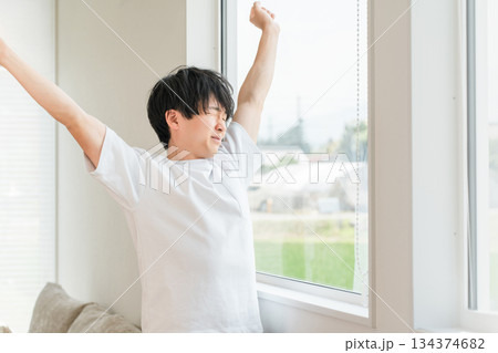 寝起き・起床時に窓辺で朝日を浴びる男性(深呼吸) 寝起き・起床時に窓辺で朝日を浴びる男性(深呼吸) 134374682