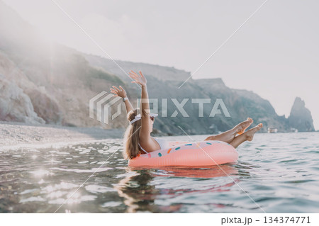 Woman, donut float, beach. Happy woman relaxing on donut float enjoying summer vacation at sea Woman, donut float, beach. Happy woman relaxing on donut float enjoying summer vacation at sea 134374771