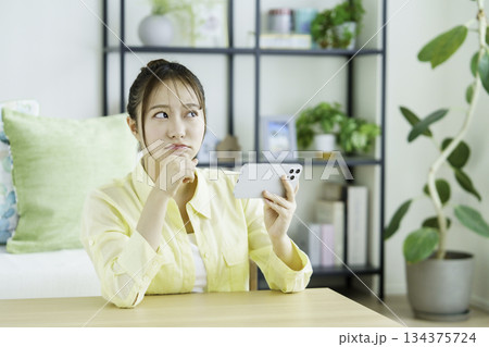 リビングでスマホで動画を視聴する考える日本人女性のポートレート リビングでスマホで動画を視聴する考える日本人女性のポートレート 134375724