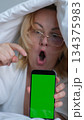 green screen for chroma key advertising Shocked lady staring at smartphone with open mouth. Middle-aged woman reading surprising message on phone, amazing news at night 134375983