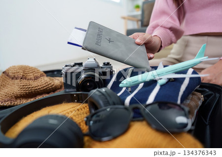 Travel Essentials. Woman packing a suitcase with passport and camera. Travel Essentials. Woman packing a suitcase with passport and camera. 134376343